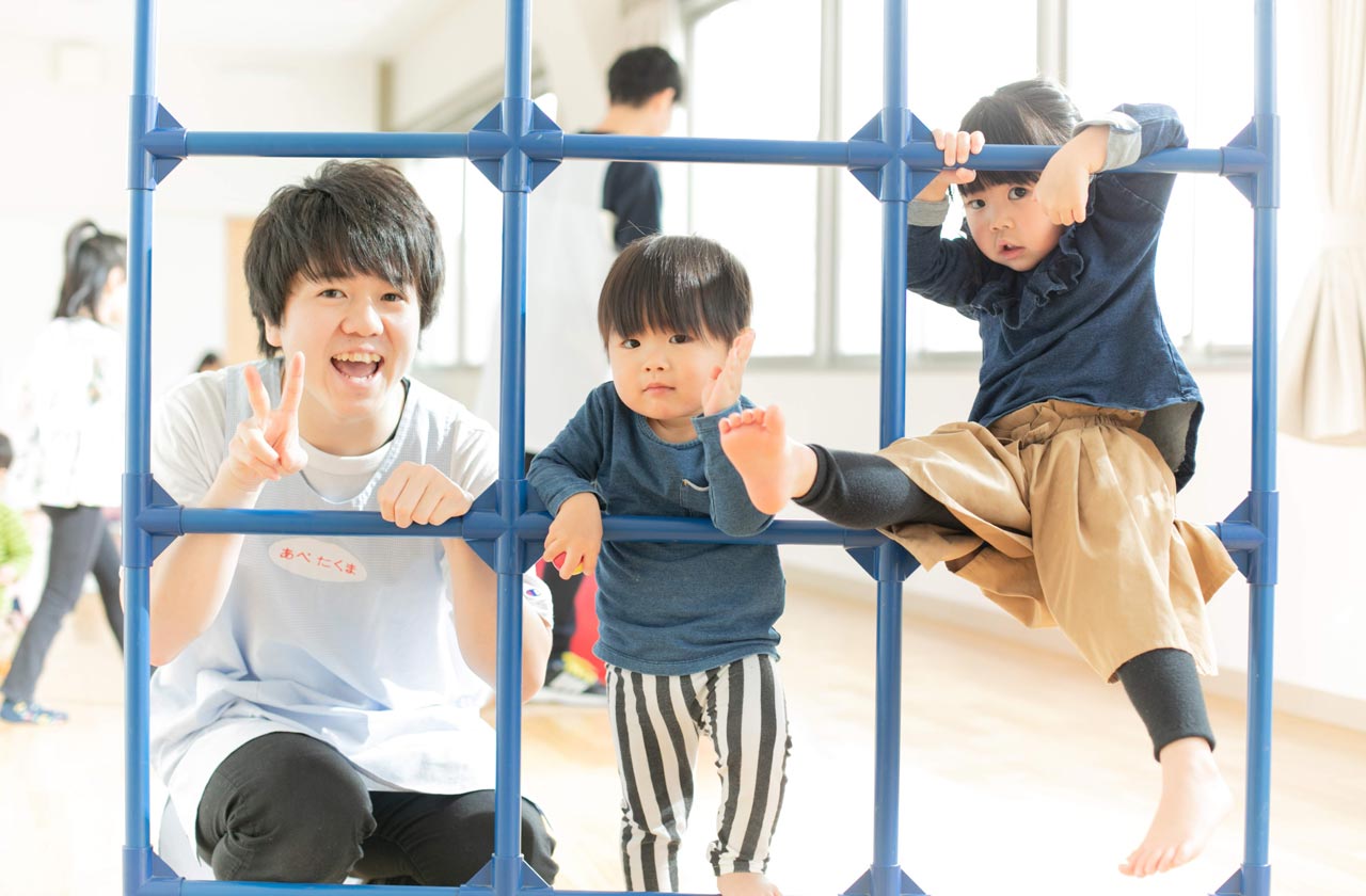 ジャングルジムで遊ぶ保育士と子供